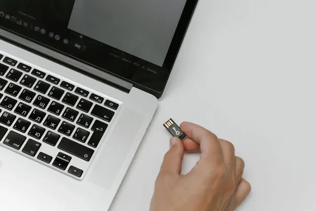 uma mão conectando um arquivo em pendrive em um laptop